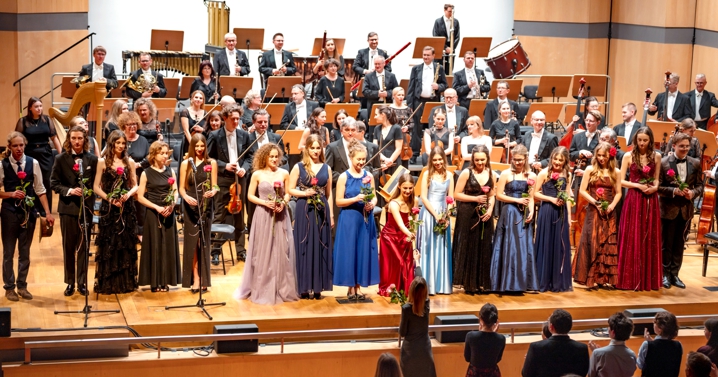 orkiestra i trzy wokalistki na scenie sali koncertowej